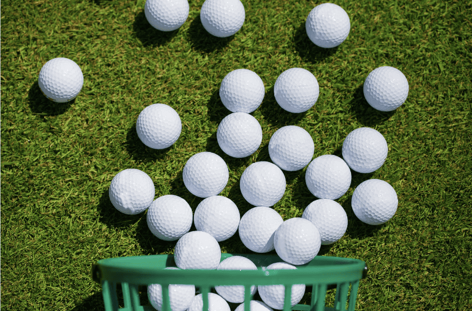 A bucket of golf balls laid out on grass.